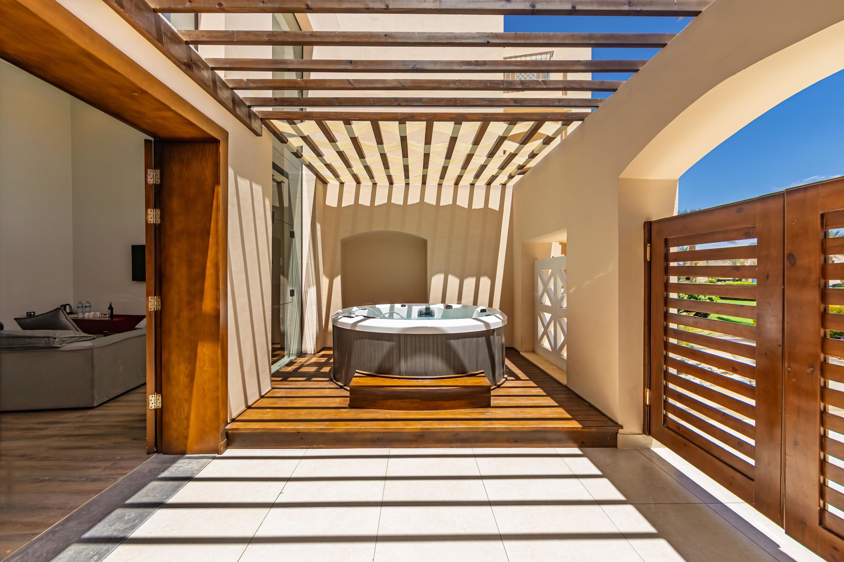 A spa area with a hot tub, wooden flooring, and a pergola structure.