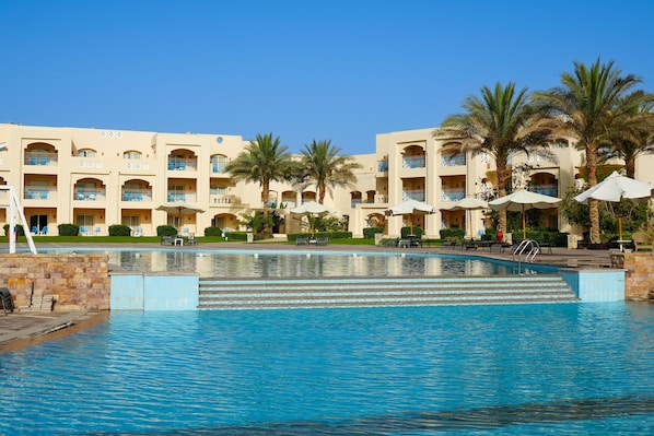 A hotel with a swimming pool, palm trees, and outdoor seating areas. - Sataya Resort Marsa Alam (Marsa Alam)