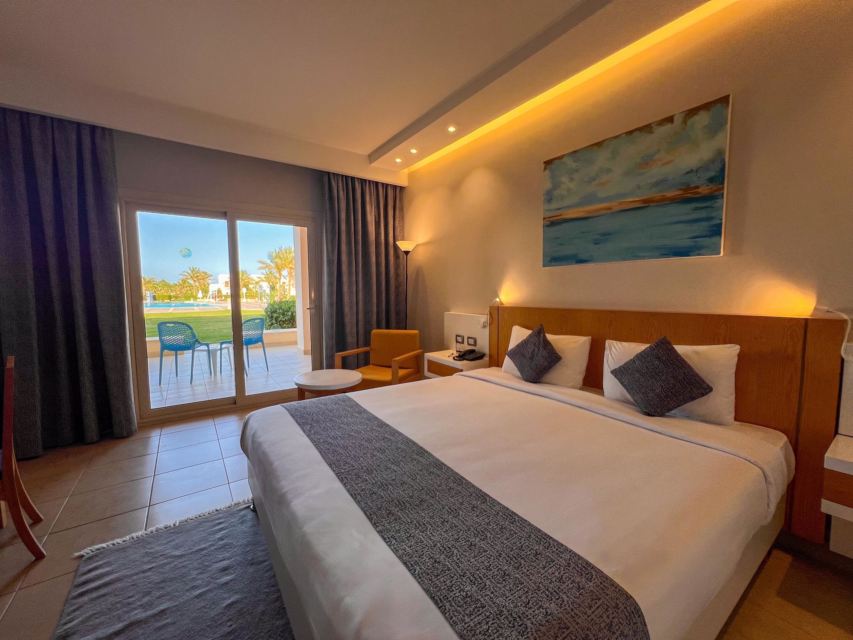 Habitación de hotel con una cama grande, un escritorio, una silla y vistas al exterior.