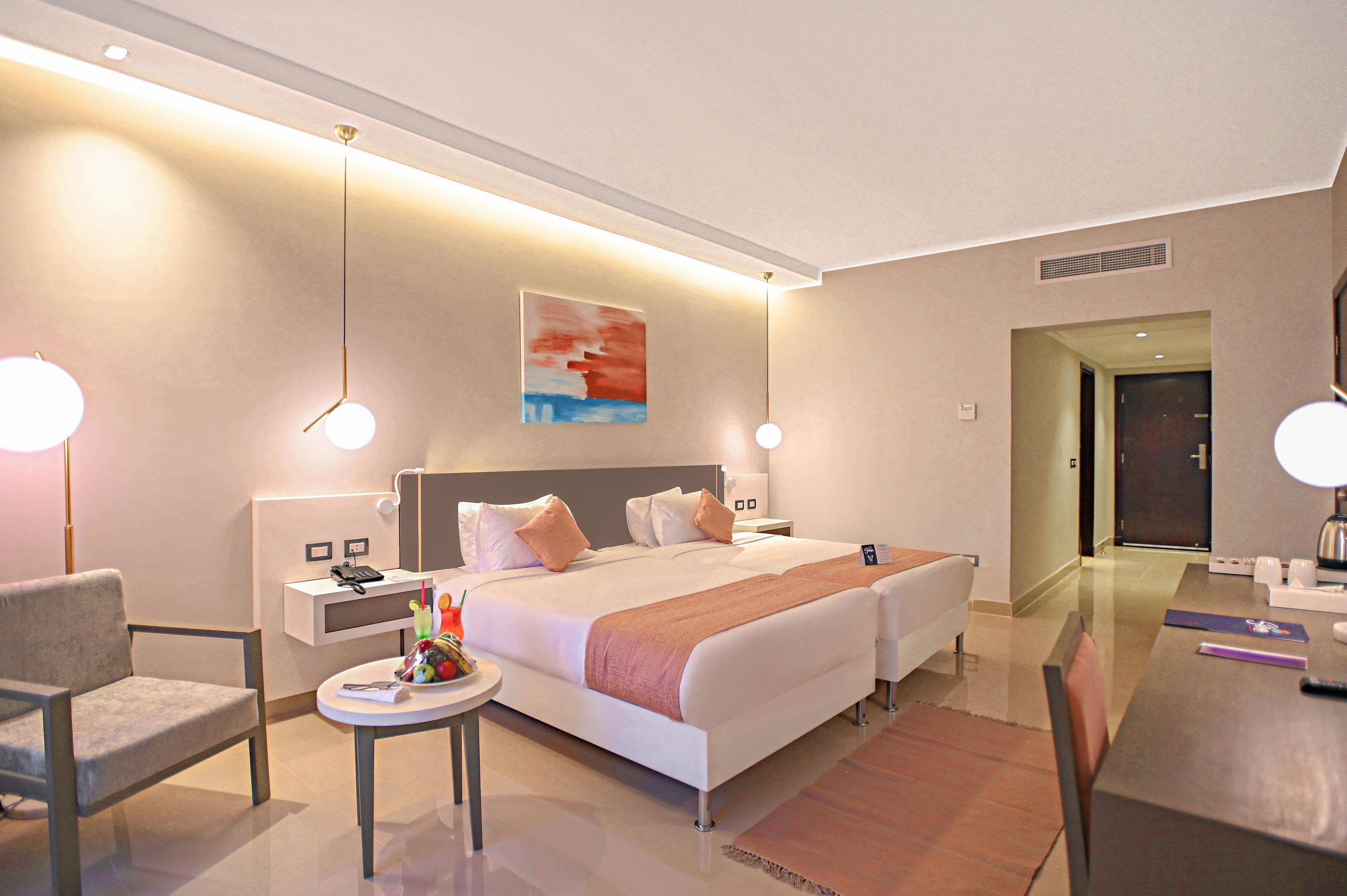 A modern hotel room with a large bed, bedside tables, a desk, and a chair.