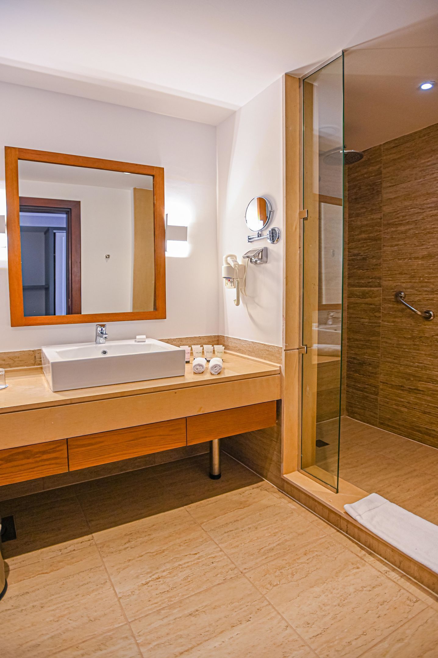 Un baño moderno con un espejo grande, un lavabo y una ducha con mampara de vidrio.