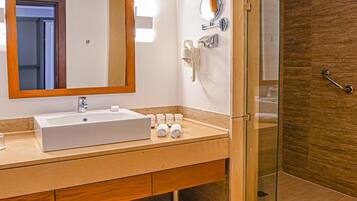 Un baño moderno con un espejo grande, un lavabo y una ducha con mampara de vidrio.
