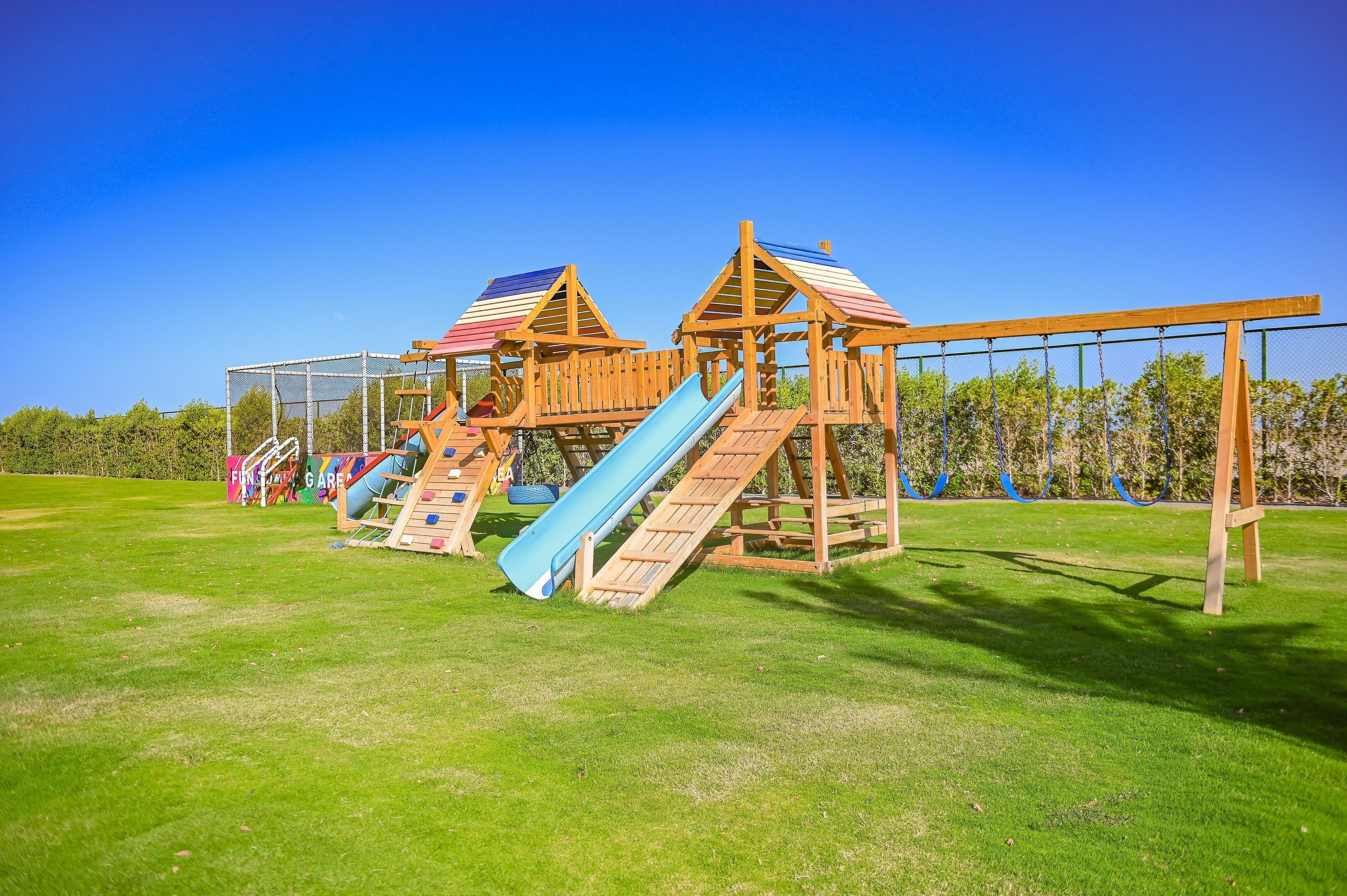 A playground with two slides and a climbing structure.