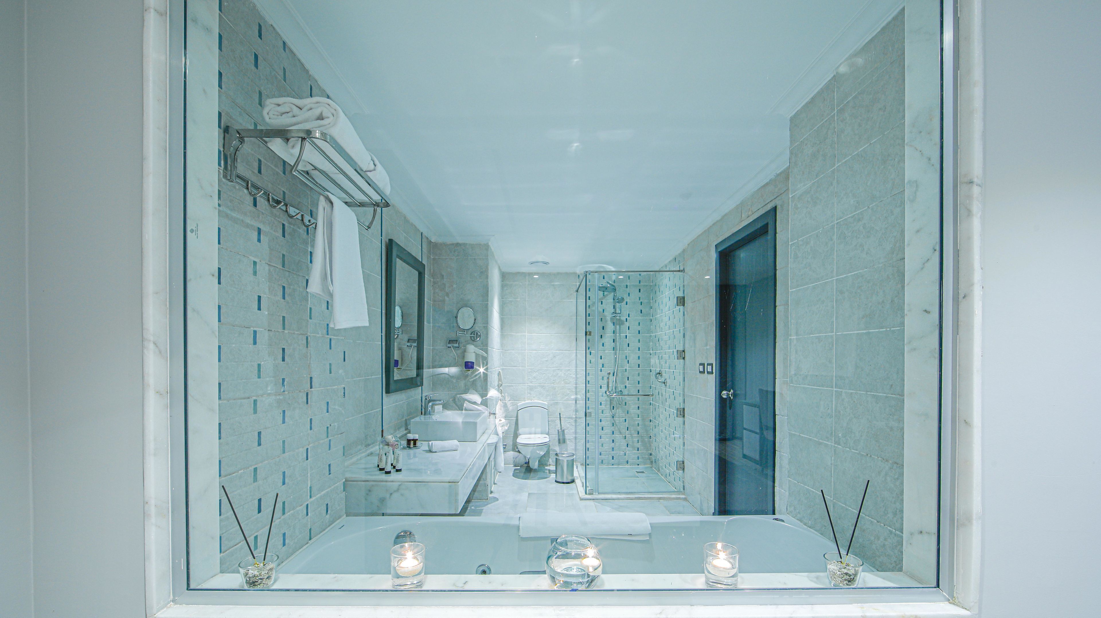 A modern bathroom with a large mirror, two sinks, and a shower area.