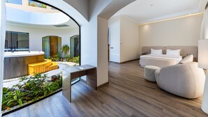 Een moderne hotelkamer met een gebogen plafond, een zithoek met een kleine tafel, een groot bed en uitzicht op het buitengebied.