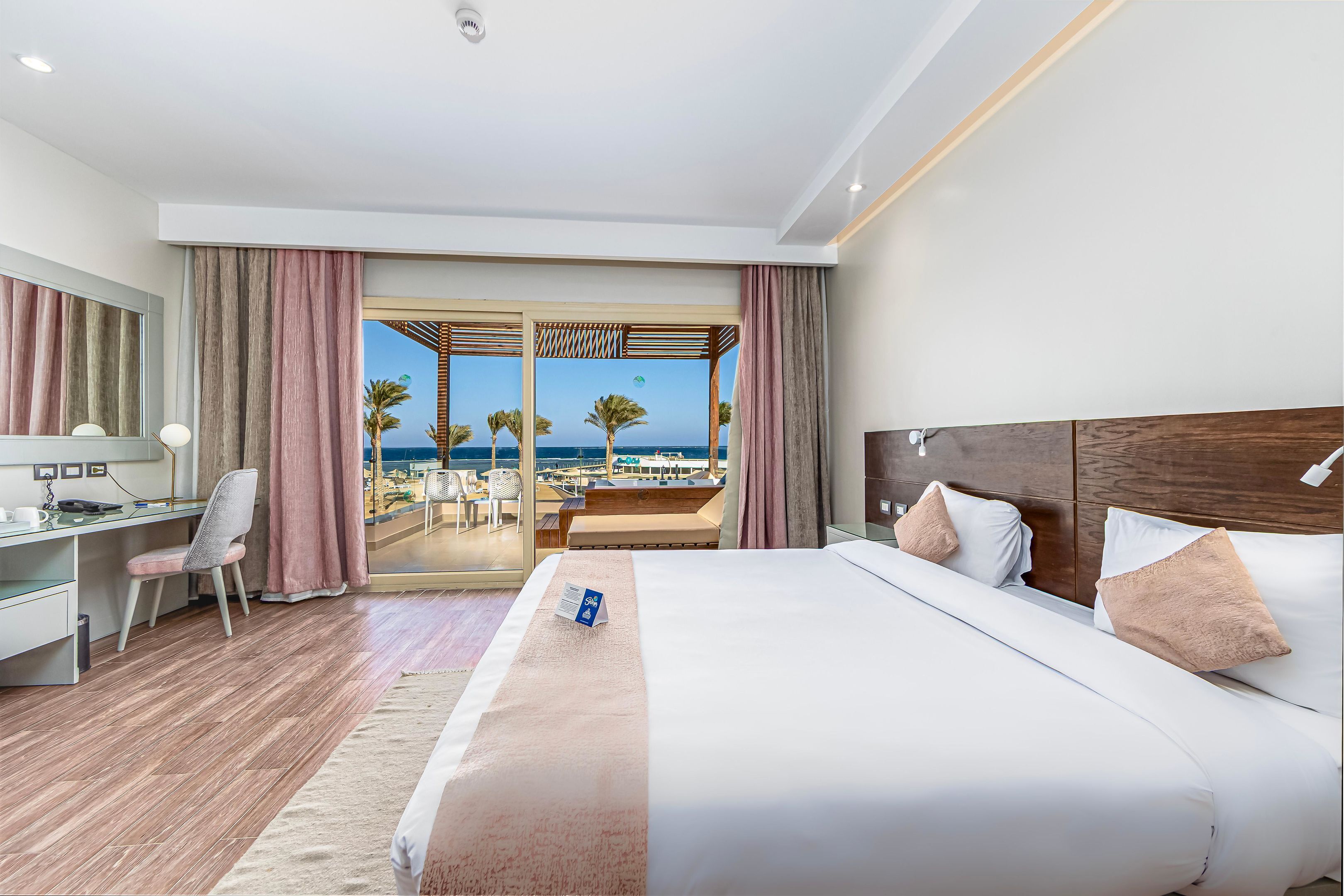 Une chambre d’hôtel équipée d’un lit, d’un bureau, d’une chaise et offrant une vue sur la plage et l’océan.