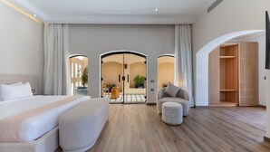 Een moderne hotelkamer met een groot bed, een zithoek en uitzicht op de gang.