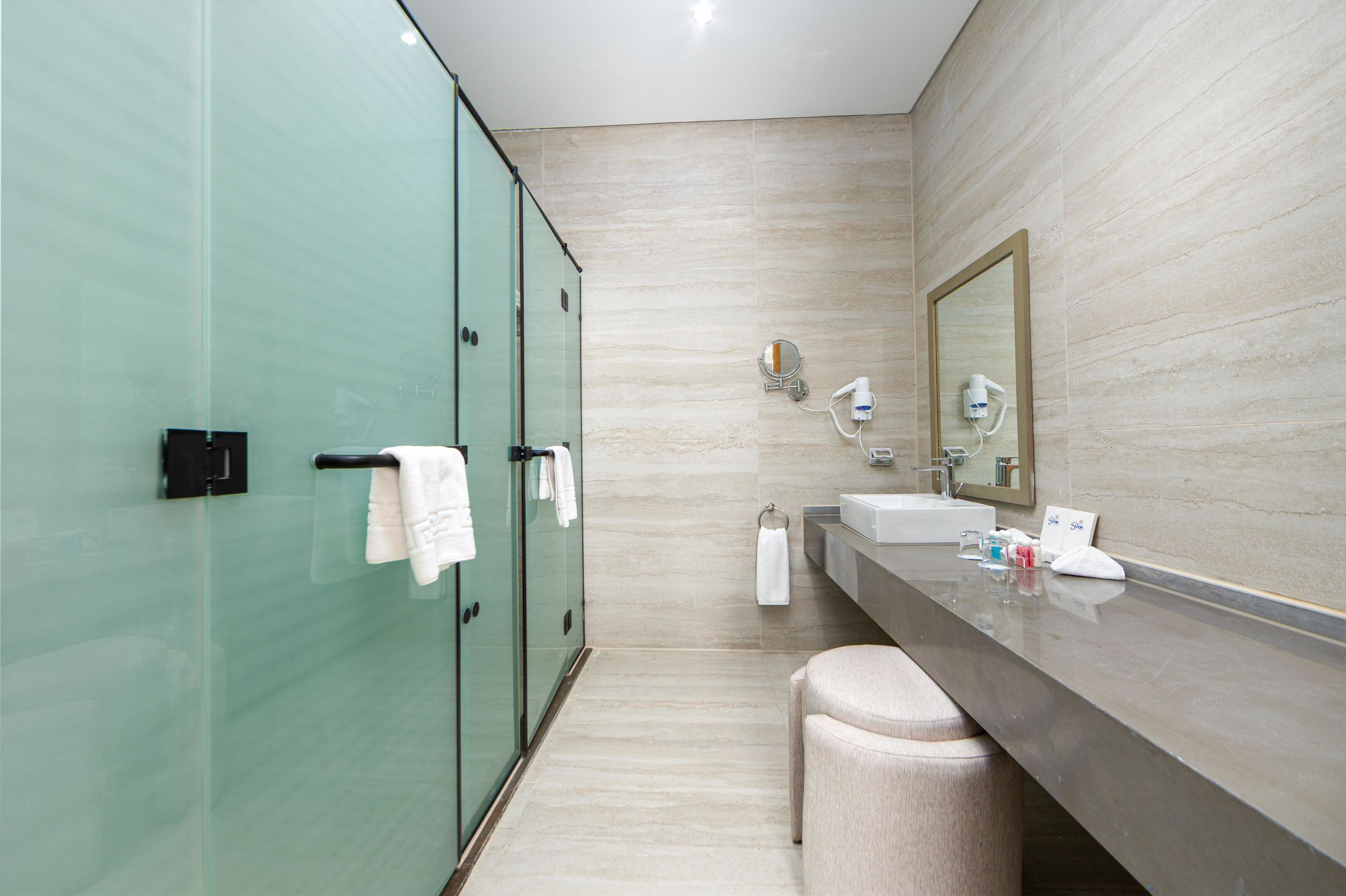 A modern bathroom with a glass shower enclosure, a vanity with a mirror, and a towel rack.