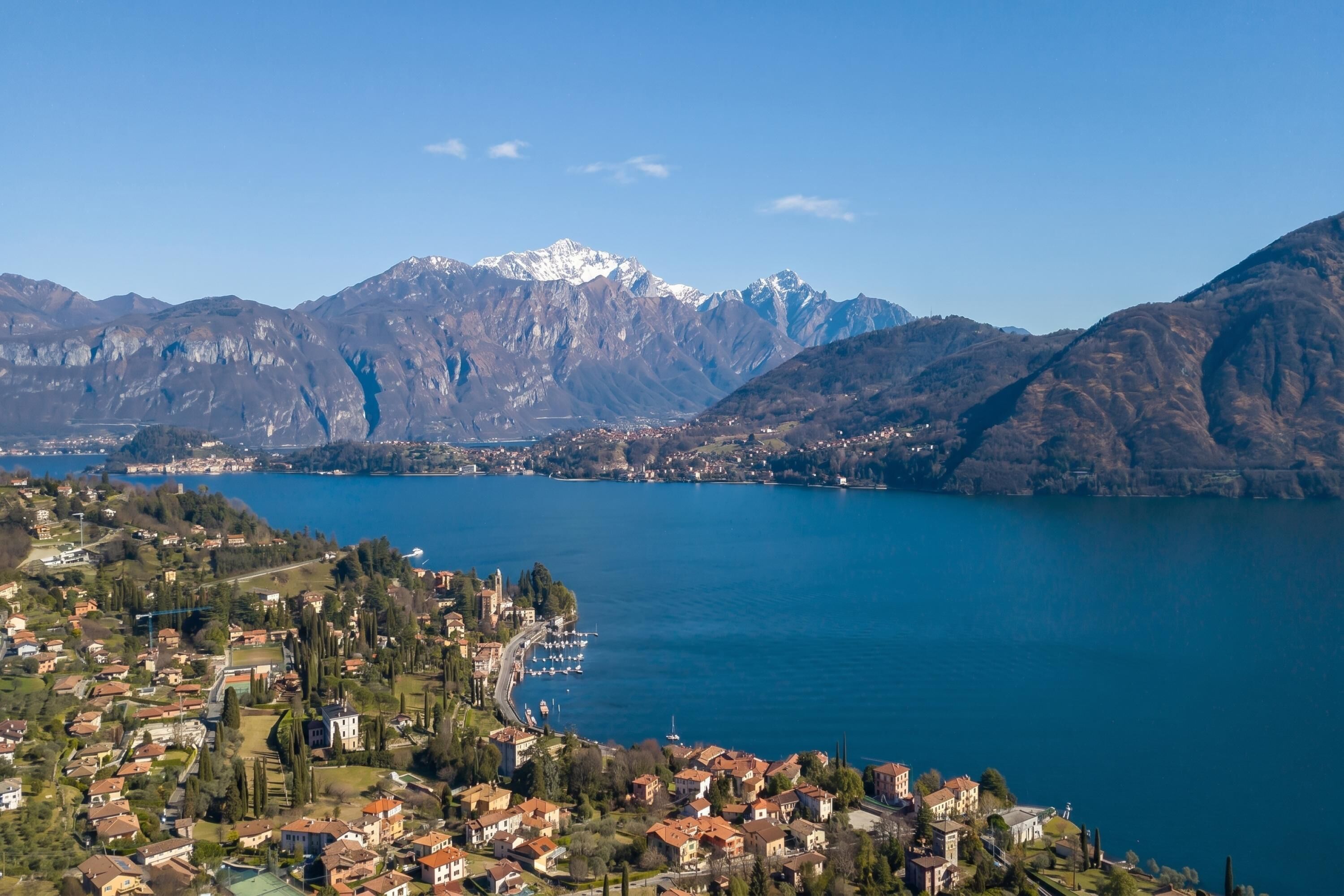Eine Stadt am See mit Bergkulisse, Wohnhäusern und einem Yachthafen.