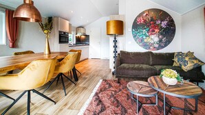 Un salon moderne avec un coin repas, un grand tableau rond et une cuisine en arrière-plan.