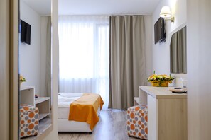 A hotel room with a bed, a desk, a TV, and a window with curtains. - Garden Nevis - All Inclusive (Sunny Beach)