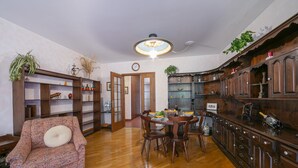 A dining area with a wooden table and chairs, surrounded by wooden cabinets and shelves with various items. - Sweet Home (Lugano)