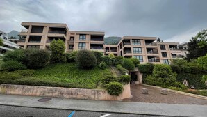 A modern multi-story residential building with balconies and a landscaped garden area. - Sweet Home (Lugano)