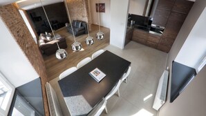 Una cocina moderna con una isla central, iluminación colgante y un comedor con mesa y sillas.