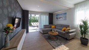 A modern living room with a grey sofa, a coffee table, and a large window. - Luxury Villa Luna Kastela (Kaštel Stari)