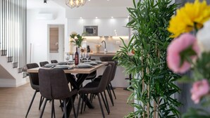 A modern dining area with a wooden table, dark chairs, and a hanging light fixture. - Luxury Villa Luna Kastela (Kaštel Stari)