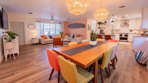Un salon moderne avec une table à manger en bois, des chaises colorées et une grande fenêtre.