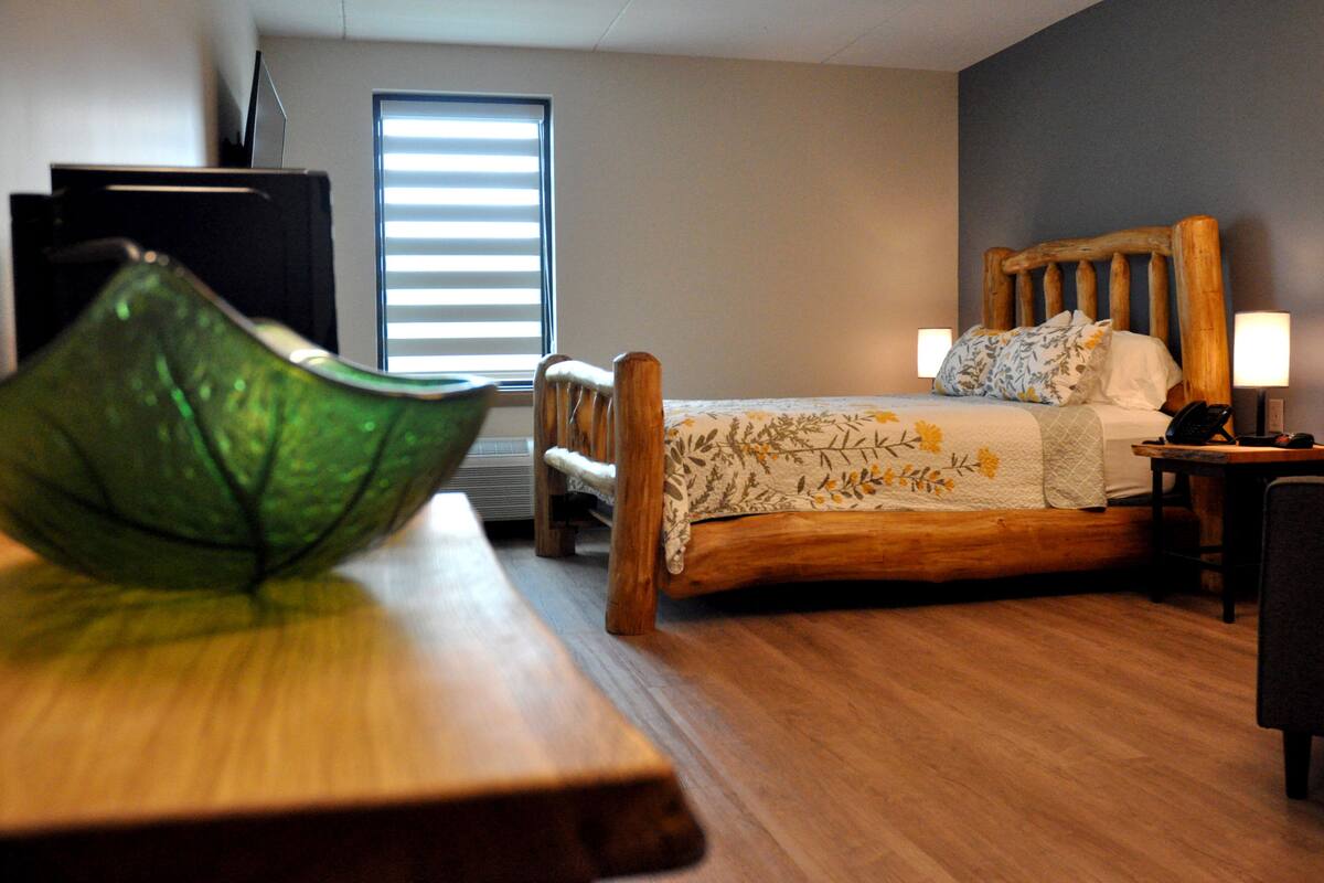 A bedroom with a wooden bed, a desk, and a green decorative bowl.