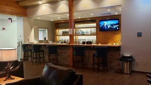 Zona de bar con pantalla de televisión, taburetes y un cubo de basura.