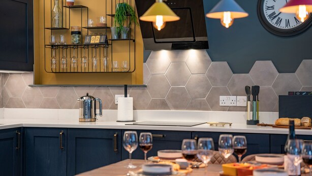 Una cocina moderna con estante de madera, hervidor y mesa lista para una comida.
