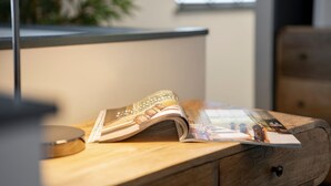 Un escritorio de madera con una revista, una lámpara y una planta al fondo.