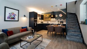 Un apartamento moderno con sala de estar, comedor, cocina y una escalera.