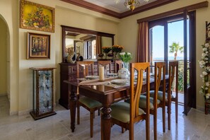 A dining room with a wooden table set for four, a large mirror, and a view of the outdoors through a sliding glass door.