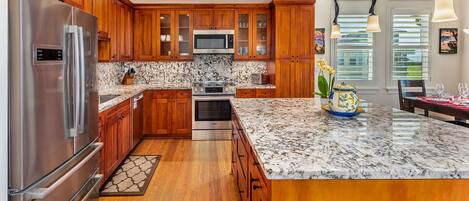 A modern kitchen with wooden cabinets, stainless steel appliances, and a granite countertop.