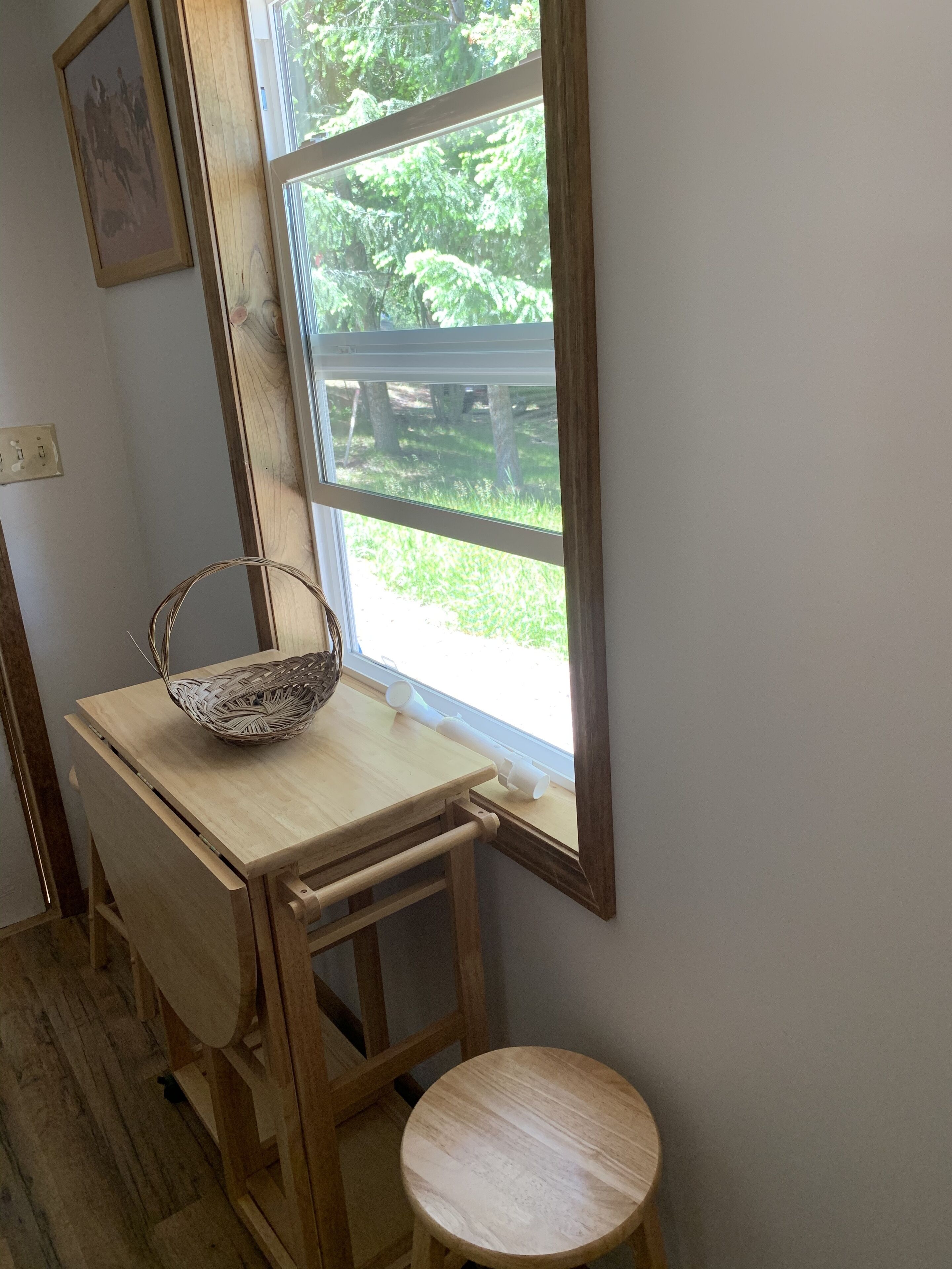 A corner of a room with a wooden desk, a wicker basket, and a small stool.