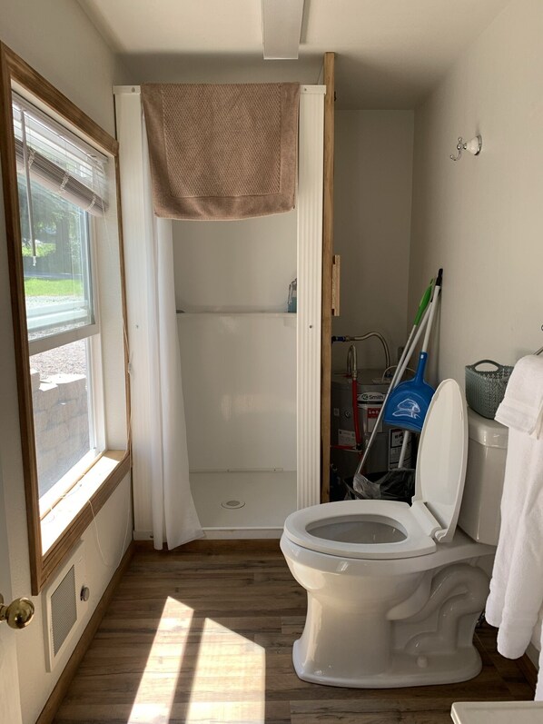 Un baño pequeño con inodoro, ducha y ventana.
