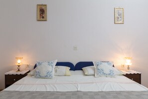 A double bed with white bedding and blue headboard, flanked by two bedside tables with lamps. - A 1 - apt Near Beach With Patio, Parking and Grill (Split)