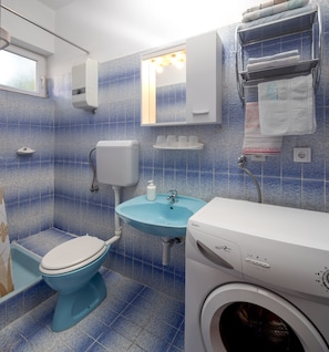 A bathroom with a blue toilet, a sink, and a washing machine. - A 1 - apt Near Beach With Patio, Parking and Grill (Split)