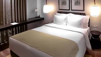 A hotel room with a large bed, a bedside table, a lamp, and two framed pictures on the wall.