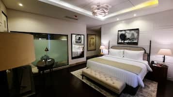 Ein modernes Hotelzimmer mit einem großen Bett, Nachttischen, einer Bank und Kunstwerken an den Wänden.