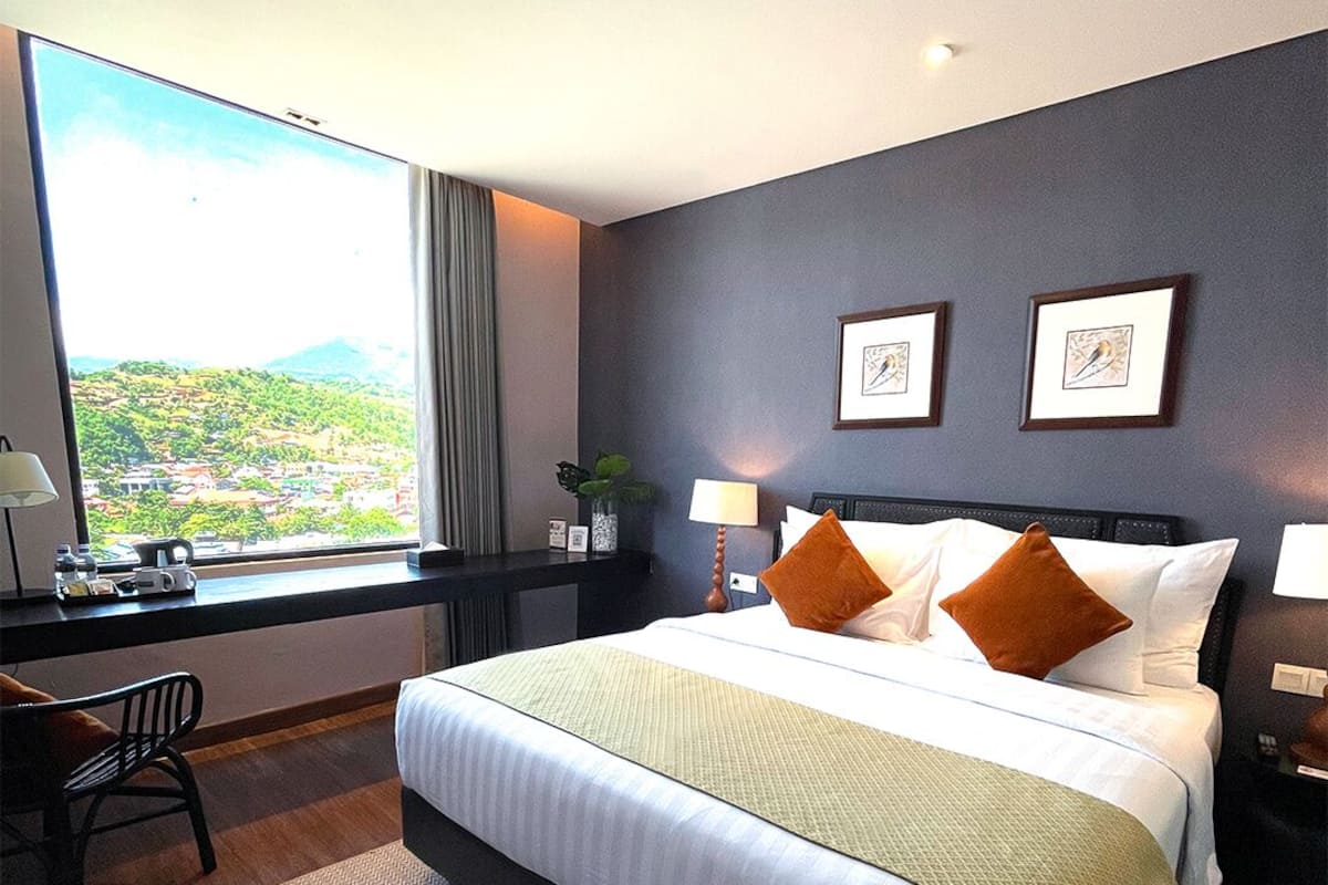 Une chambre d’hôtel avec un grand lit, un bureau et une vue sur un paysage montagneux.