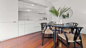 A modern kitchen with white cabinetry, a round dining table with black chairs, and a mirror on the wall. - Perfect Laneway Terrace, Surry Hills (Surry Hills)