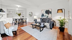 A modern living room with a grey sofa, a coffee table, and a dining area with a table and chairs. - Perfect Laneway Terrace, Surry Hills (Surry Hills)
