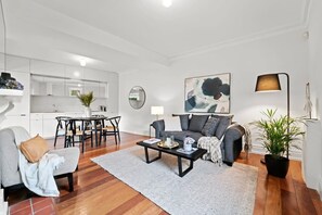 Un salon moderne avec un canapé gris, une table basse et un coin repas comprenant une table et des chaises.