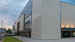 A modern building with a glass facade and a large entrance. - Comfortable Modern Studio With Shaded Patio (Split)