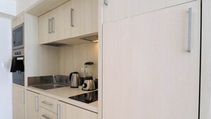 Una cocina moderna con armarios de madera clara, electrodomésticos de acero inoxidable y encimera negra.