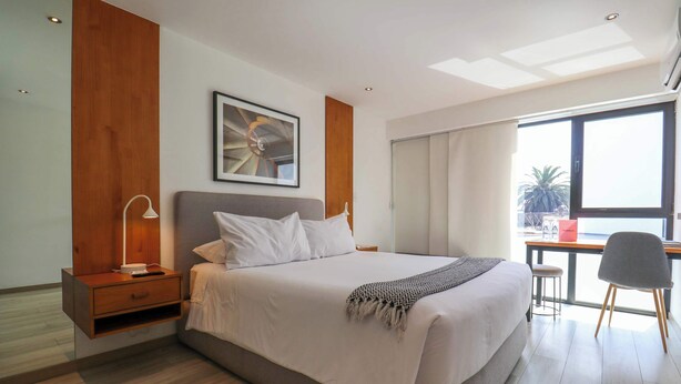 Una habitación de hotel moderna con una cama grande, un escritorio y una silla.