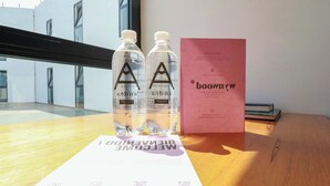 Una mesa de madera con dos botellas de agua transparentes, un folleto rosa y una guía de bienvenida.