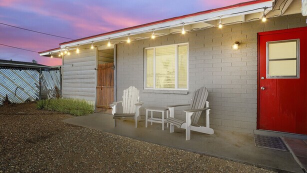 A house with a red door, a covered porch with string lights, and two Adirondack chairs. - Pinchot Tres | Old Town Scottsdale (Scottsdale)