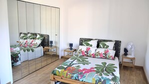 A bedroom with a bed, nightstands, a mirror, and a fan. - Quiet, Clear view, Close to Beaches and Shops, Parking & Wifi Included (Menton)