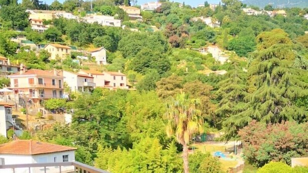 A balcony with a table and chairs, offering a view of a hillside with buildings and greenery. - Quiet, Clear view, Close to Beaches and Shops, Parking & Wifi Included (Menton)