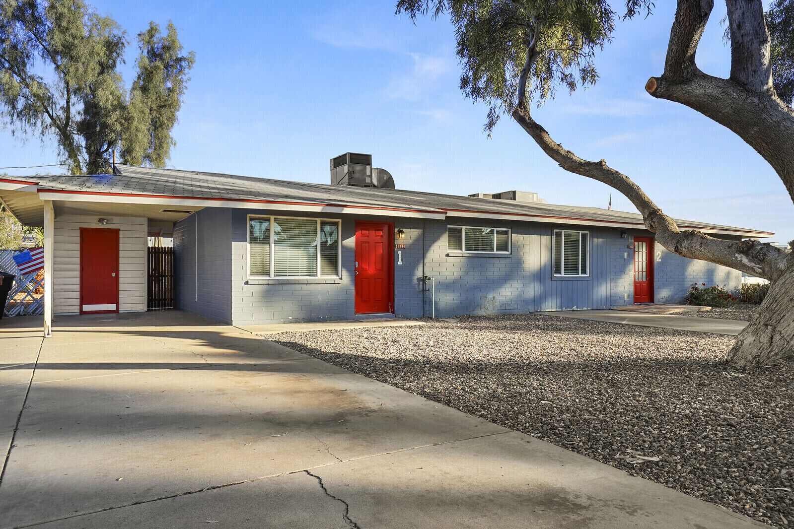 A single-story house with a red front door, a small attached garage, and a covered porch.