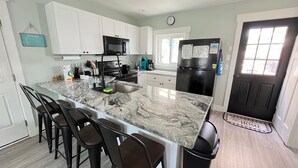 A kitchen with white cabinets, a black refrigerator, a sink, and a marble countertop. - **PRIVATE POOL** 1 Block to Beach (Kure Beach)