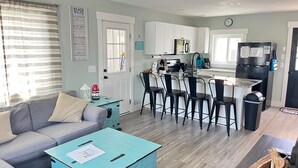 A modern kitchen with white cabinets, a black refrigerator, and a bar area with black stools. - **PRIVATE POOL** 1 Block to Beach (Kure Beach)