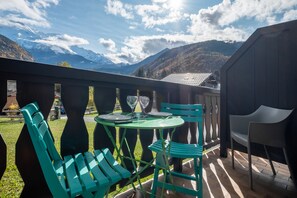 A balcony with a table and chairs, overlooking a mountainous landscape. - Studio Moderne Avec VUE (Servoz)