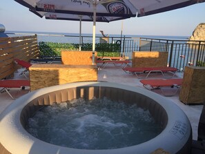Ein Whirlpool, umgeben von Holzmöbeln, mit Blick auf das Meer.